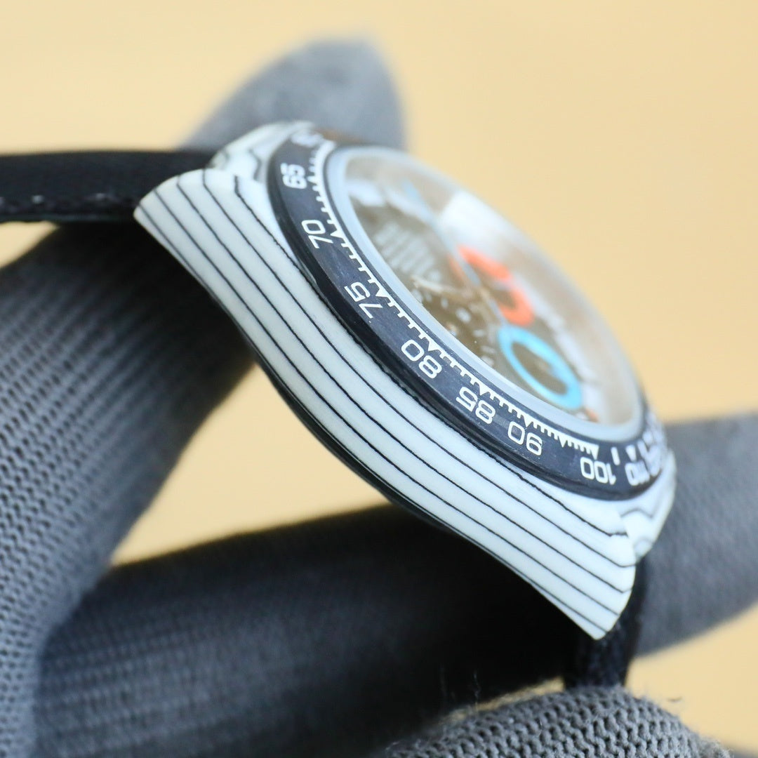 Rolex Daytona watch side view with engraved bezel and crown, on fabric strap.