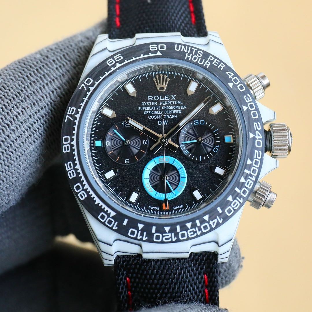 Rolex chronograph watch with black dial, turquoise subdials, stainless case, black fabric strap
