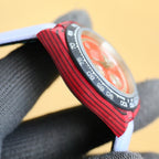 Rolex watch side profile with red bezel and black minute-track, stainless case