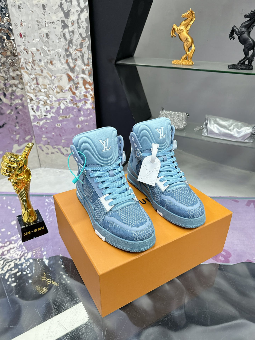 Pair of light blue high-top sneakers on orange shoe box, teal laces and emblem details
