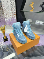 Pair of light blue high-top sneakers on orange shoe box, teal laces and emblem details