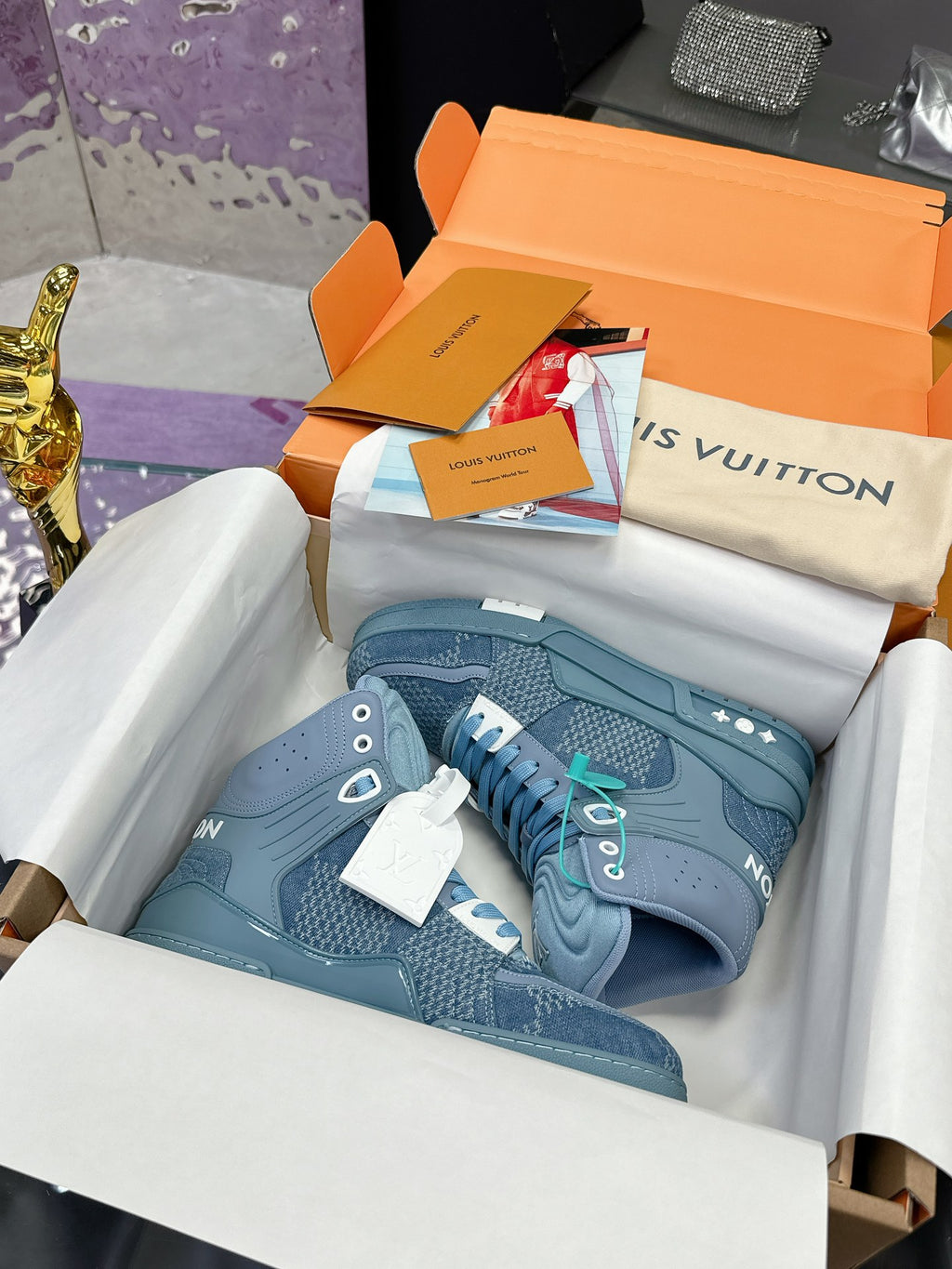 Light blue high-top sneakers in box with white and teal lace details, side logo patches