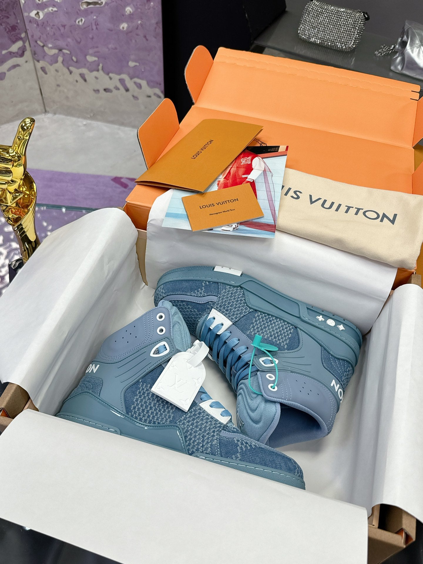Light blue high-top sneakers in box with white and teal lace details, side logo patches