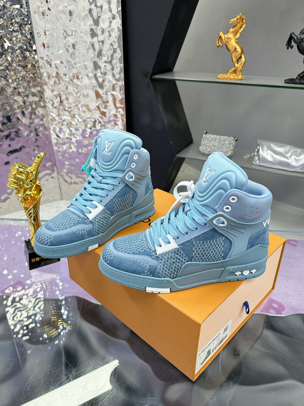 Two light blue high-top sneakers, teal laces and side emblem, displayed on orange boxes