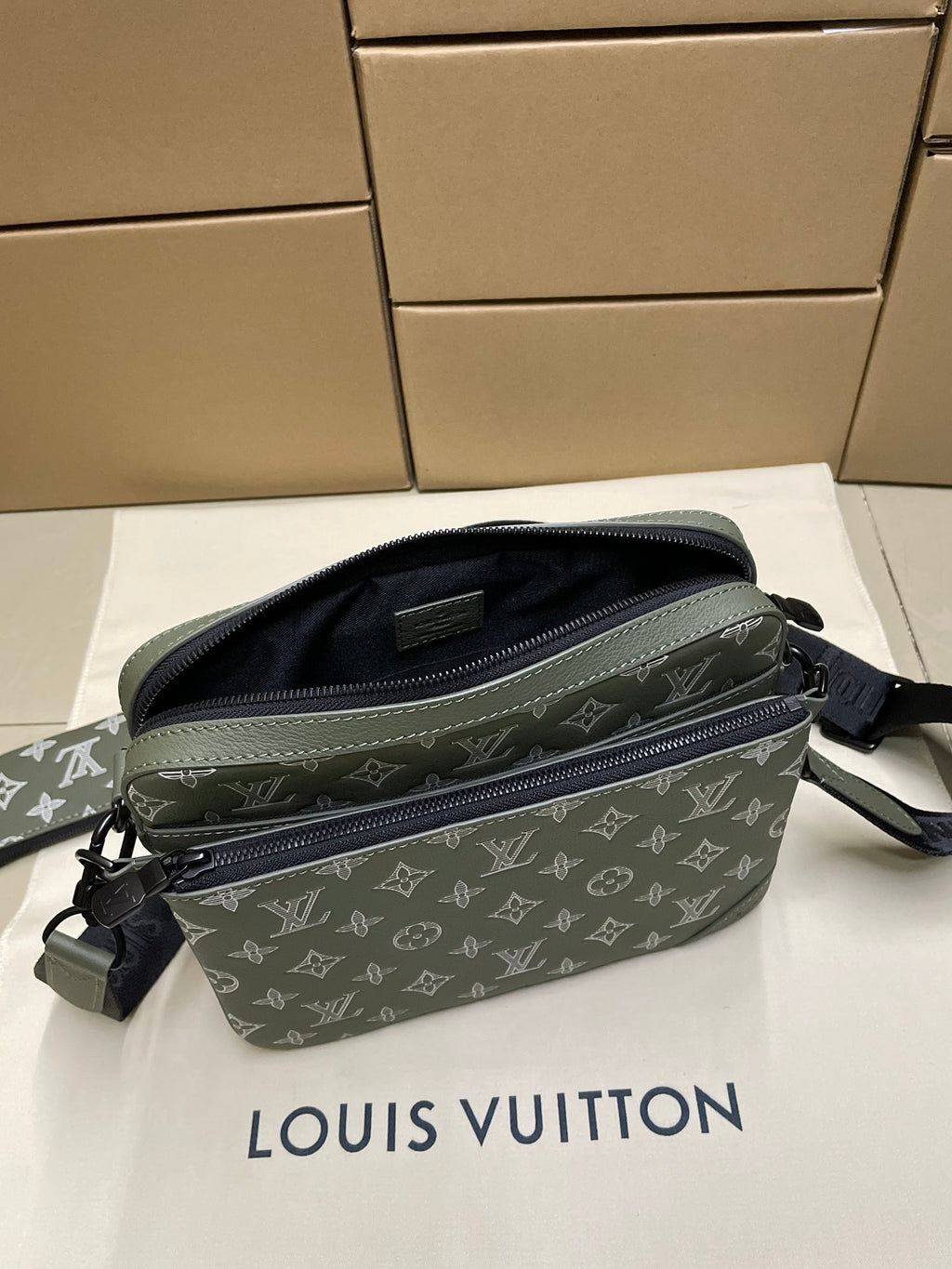 Green monogram crossbody bag angled view with open top zipper pocket