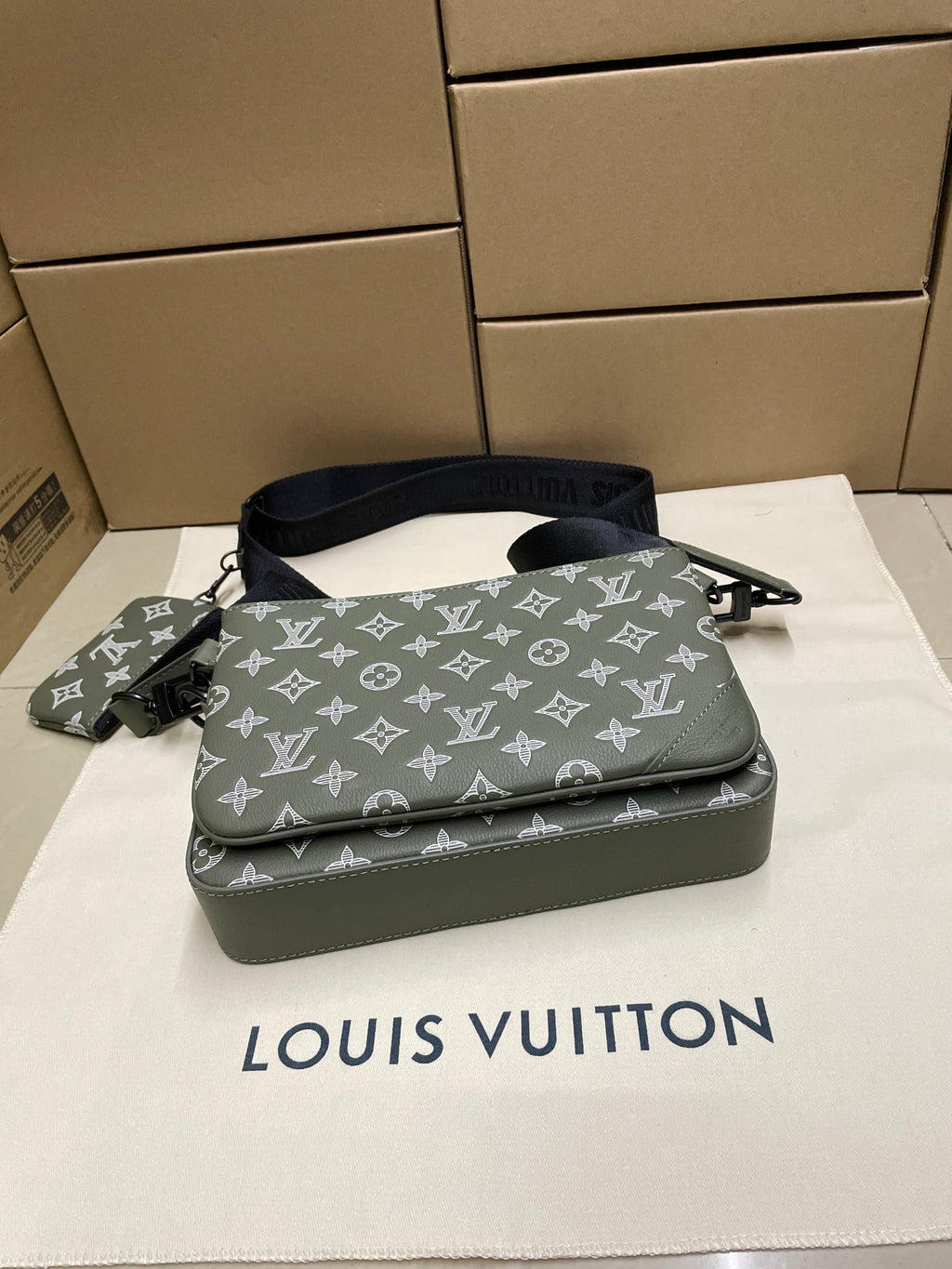 Green monogram crossbody bag top view with front zipper and navy shoulder strap