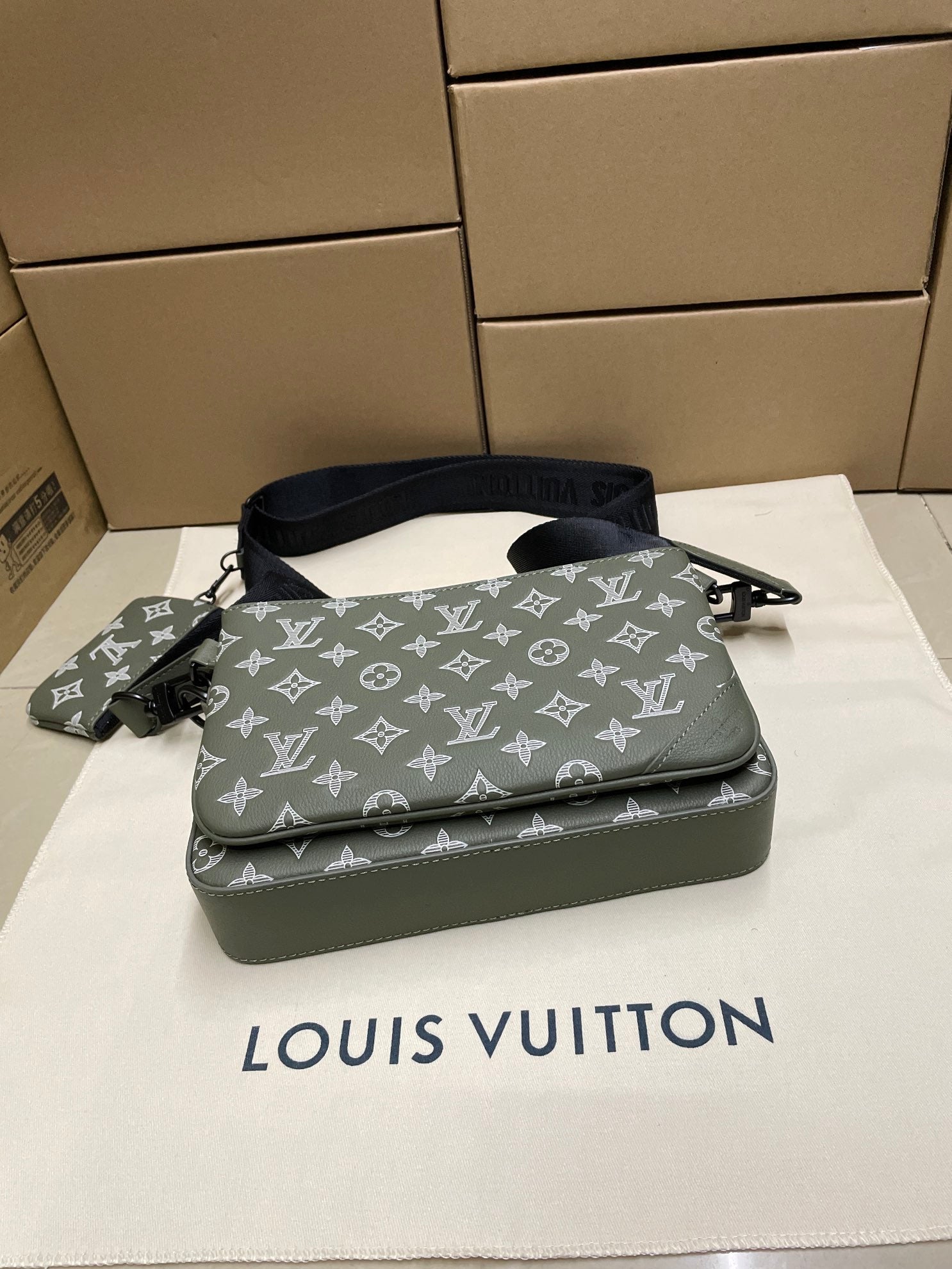 Green monogram crossbody bag top view with front zipper and navy shoulder strap