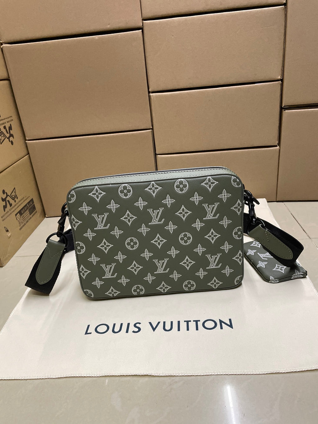Green monogram crossbody bag with zipper closure and adjustable shoulder strap