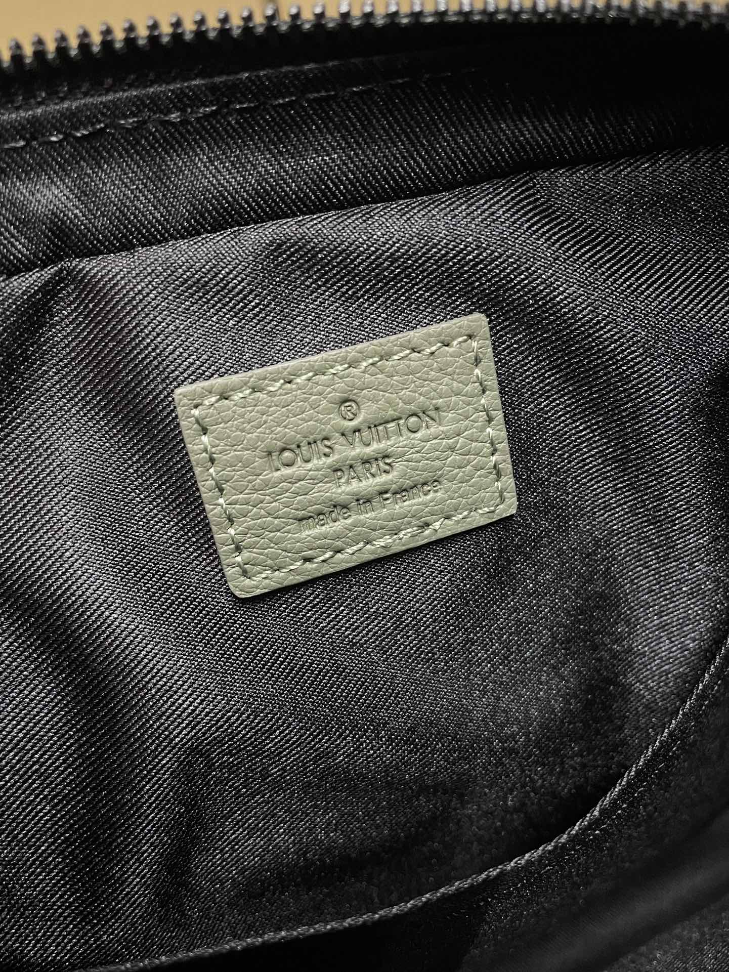 Black fabric interior with stitched logo patch reading Louis Vuitton Paris