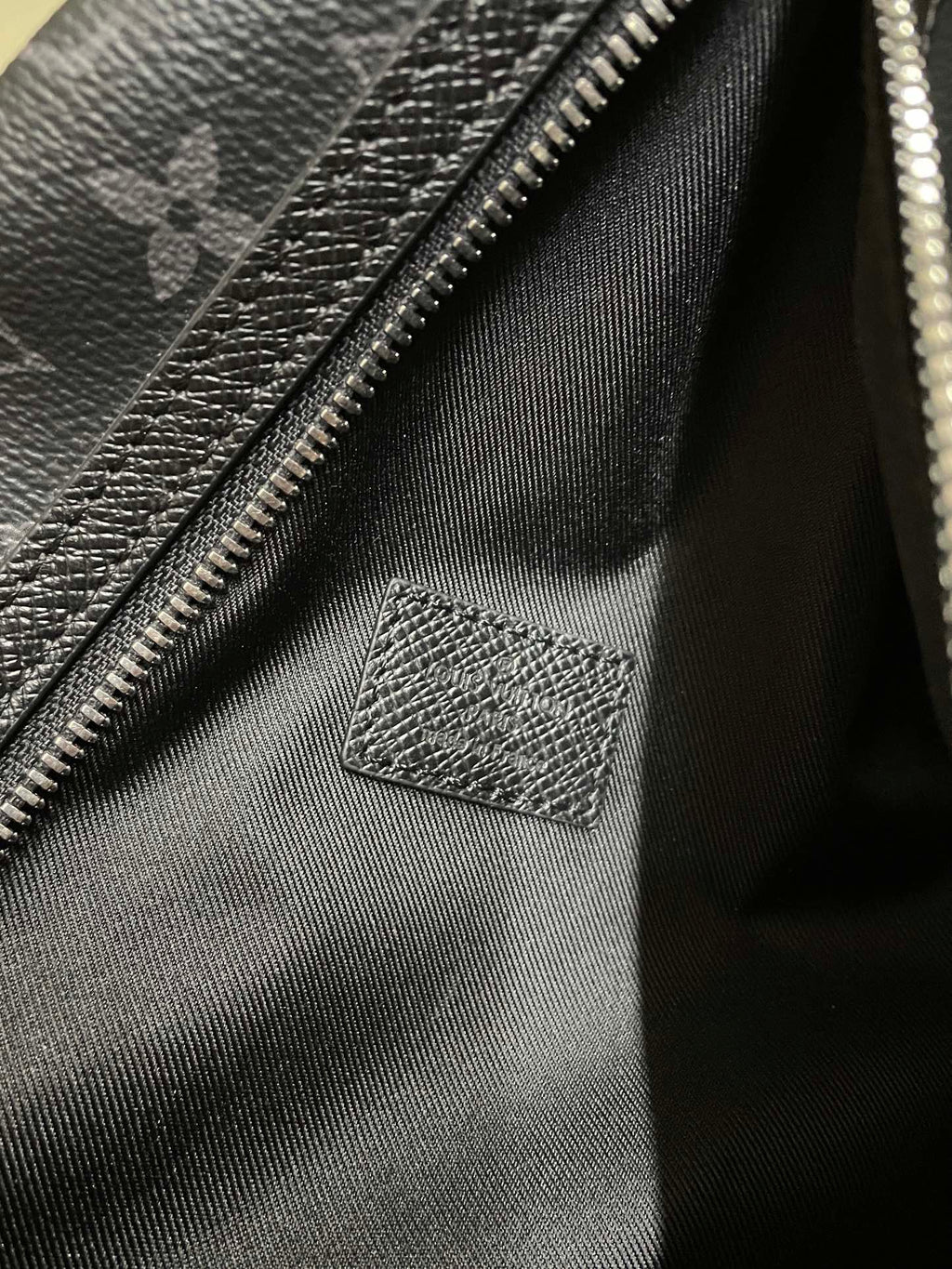 Bag interior lining with zipper track and stitched leather patch