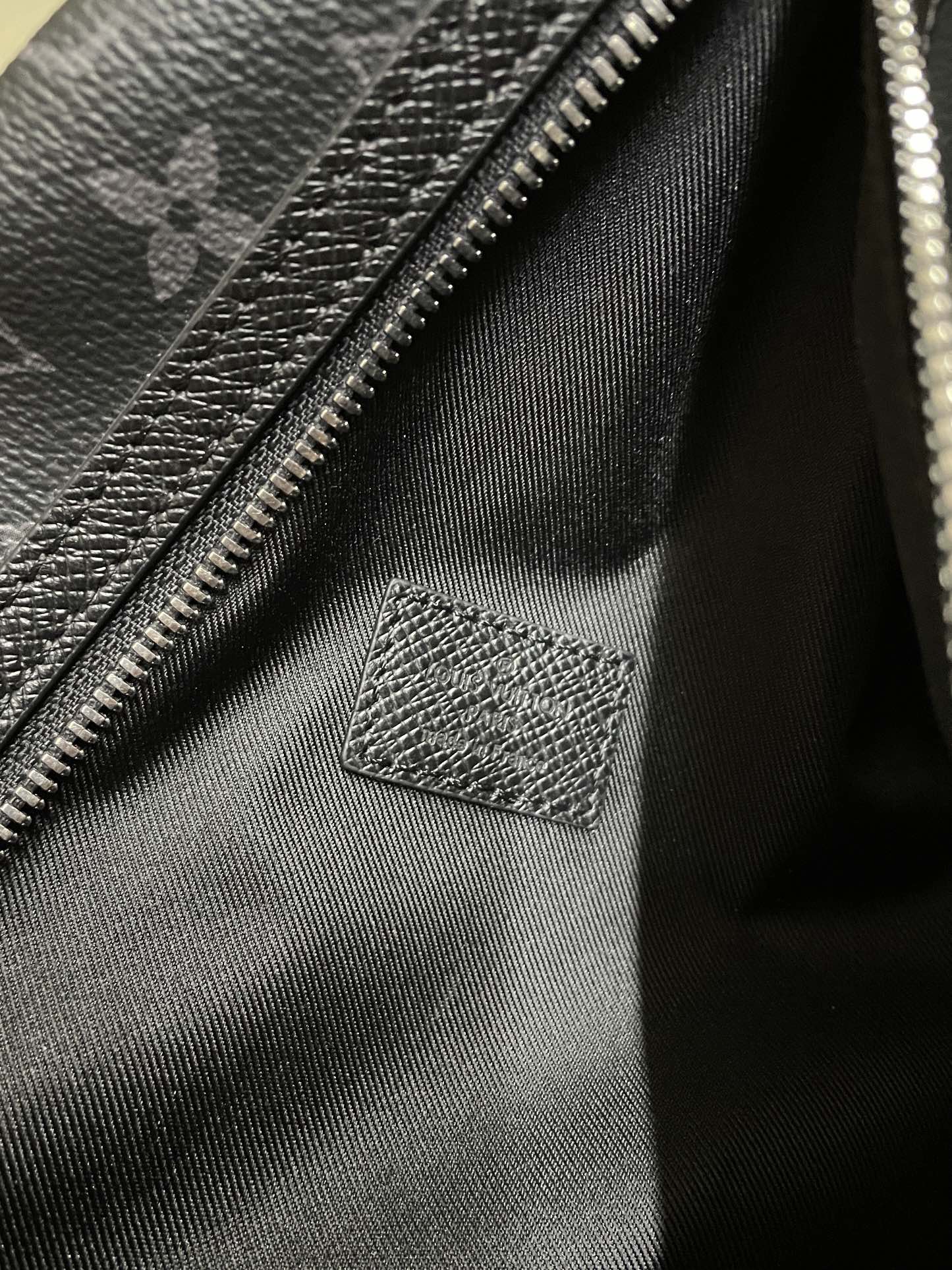 Bag interior lining with zipper track and stitched leather patch