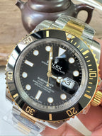 Rolex Submariner wristwatch with black dial, gold markers, two-tone metal bracelet