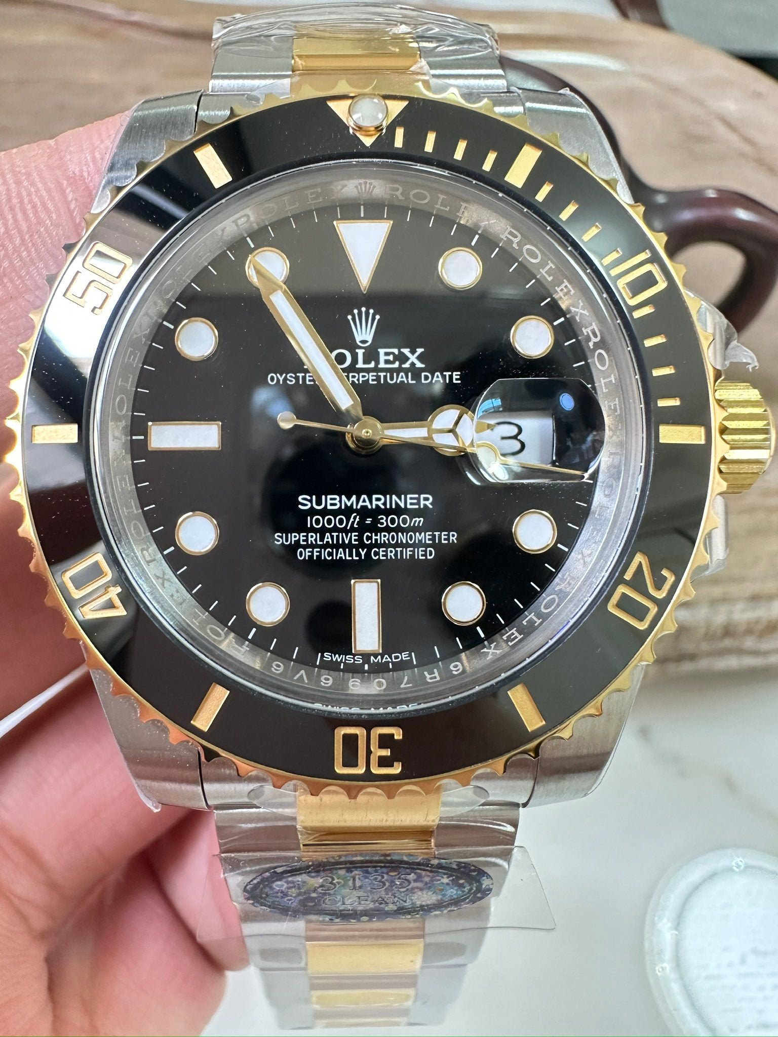 Rolex Submariner wristwatch with black dial, gold bezel, and two-tone metal bracelet