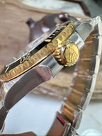 Rolex Submariner side of watch with gold accents and two-tone metal bracelet