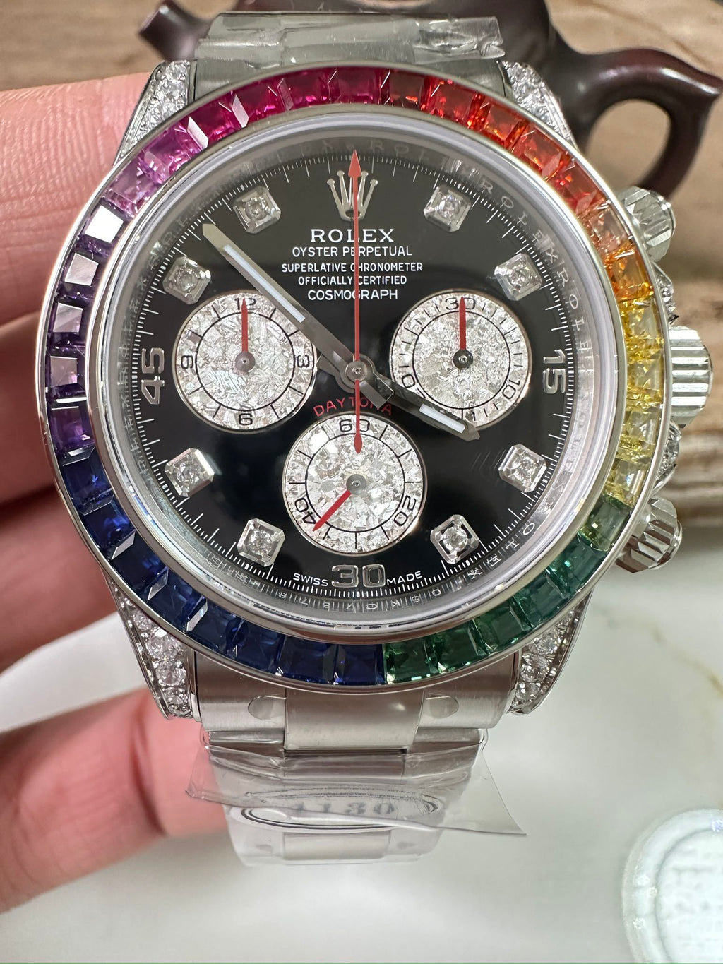 Rolex Daytona watch with black dial, three subdials, jeweled bezel, stainless bracelet