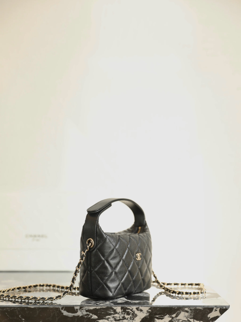 Black quilted Chanel mini handbag with top handle and gold chain strap