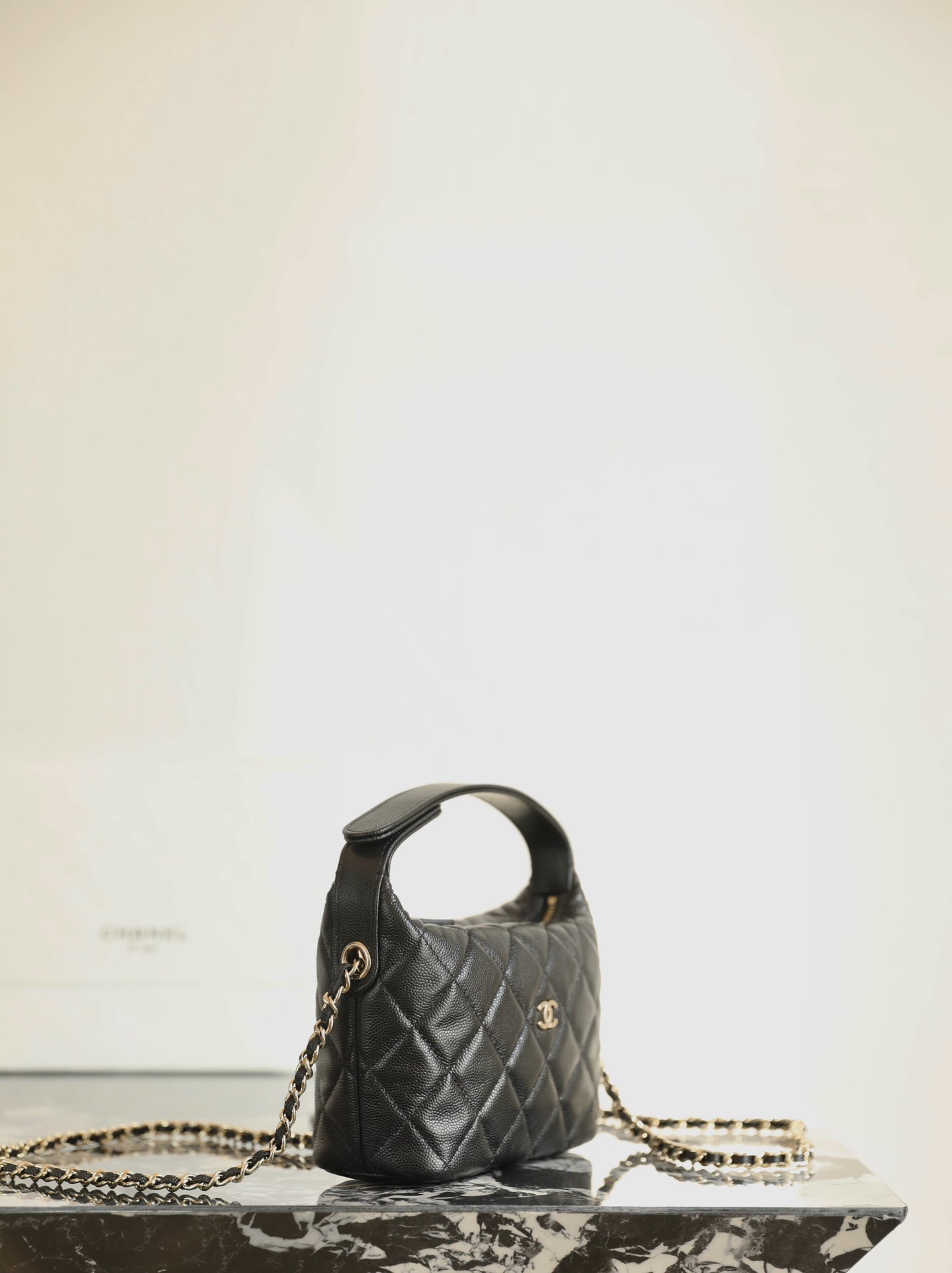 Black quilted Chanel mini handbag with top handle and gold chain strap