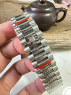 Stainless steel Rolex watch bracelet with red accents, side view
