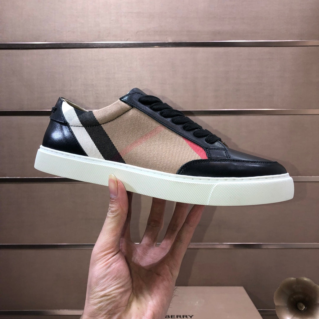 Burberry low-top sneaker held, black leather with beige panel and striped detail, white sole.