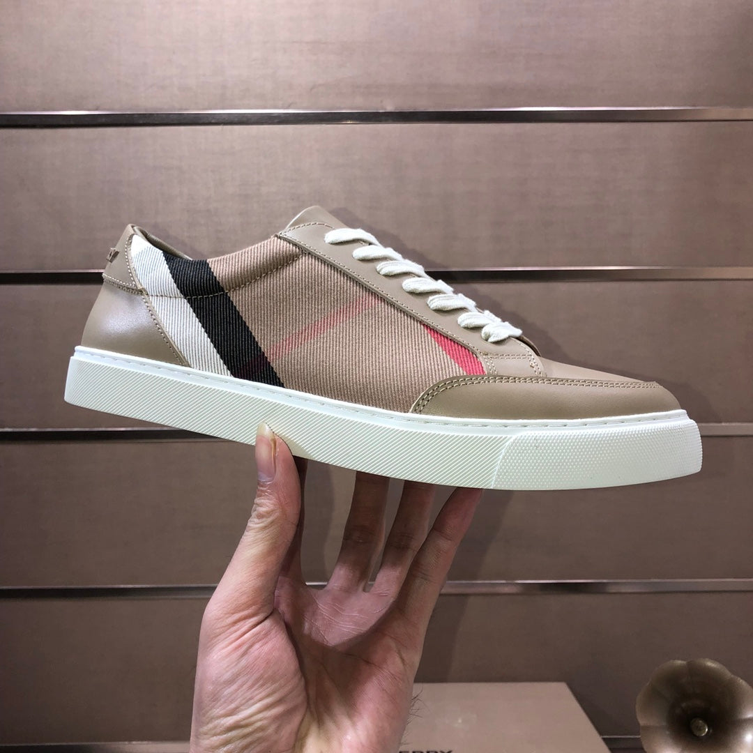 Beige low-top sneakers held up, showing side stripe and white lace-up