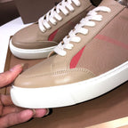 Beige low-top sneakers close-up with white laces, red logo stripe, and side panel