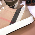 Beige sneaker close-up showing plaid side stripe and red accent