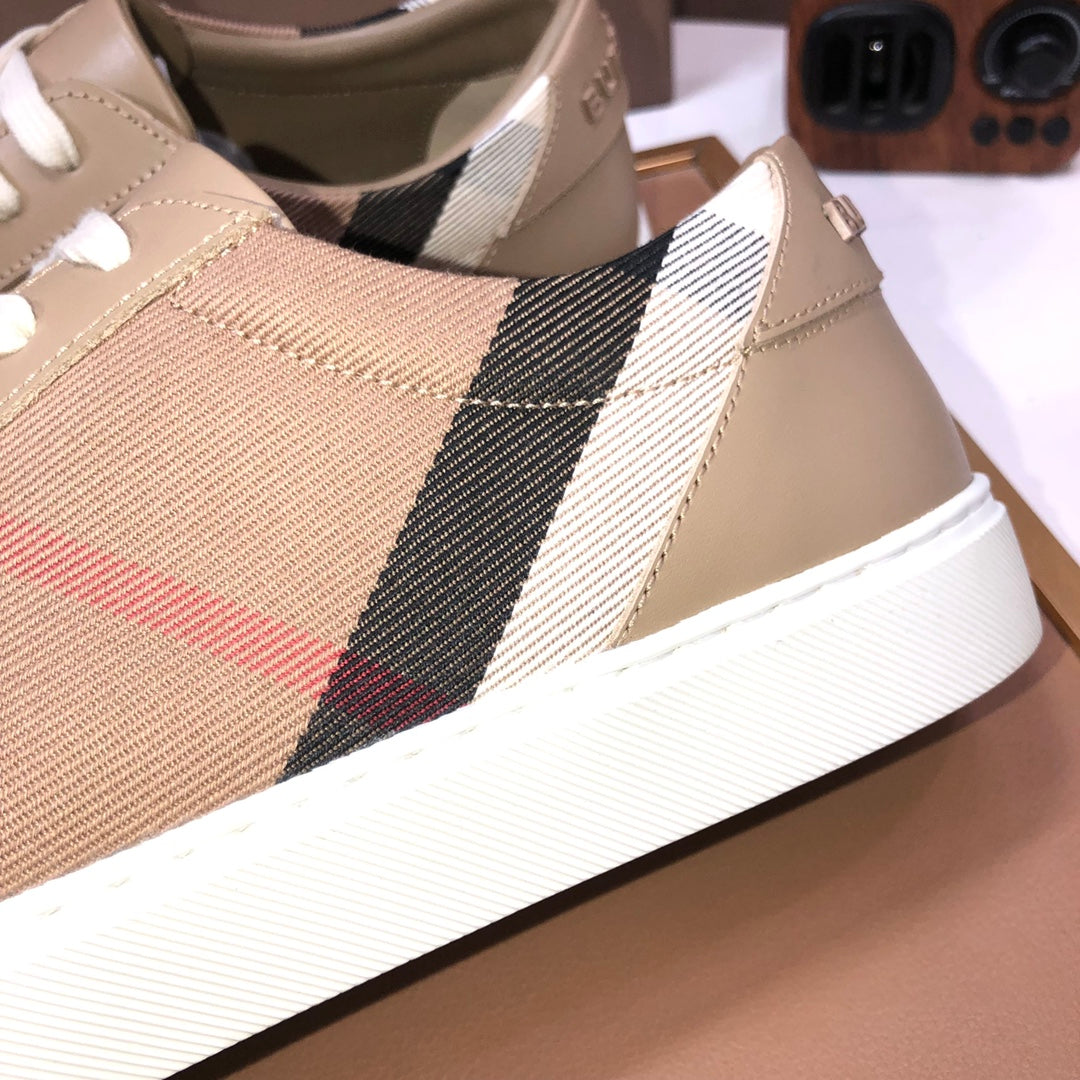 Beige sneaker close-up showing plaid side stripe and red accent