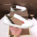 Burberry low-top sneakers with white leather and tan check side stripe, held in hand