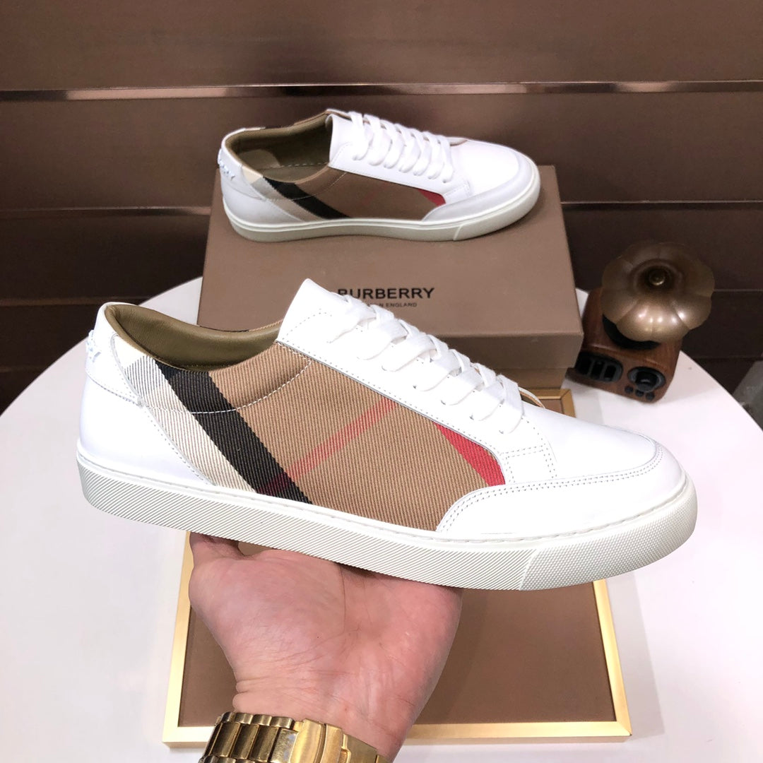 Burberry low-top sneakers with white leather and tan check side stripe, held in hand