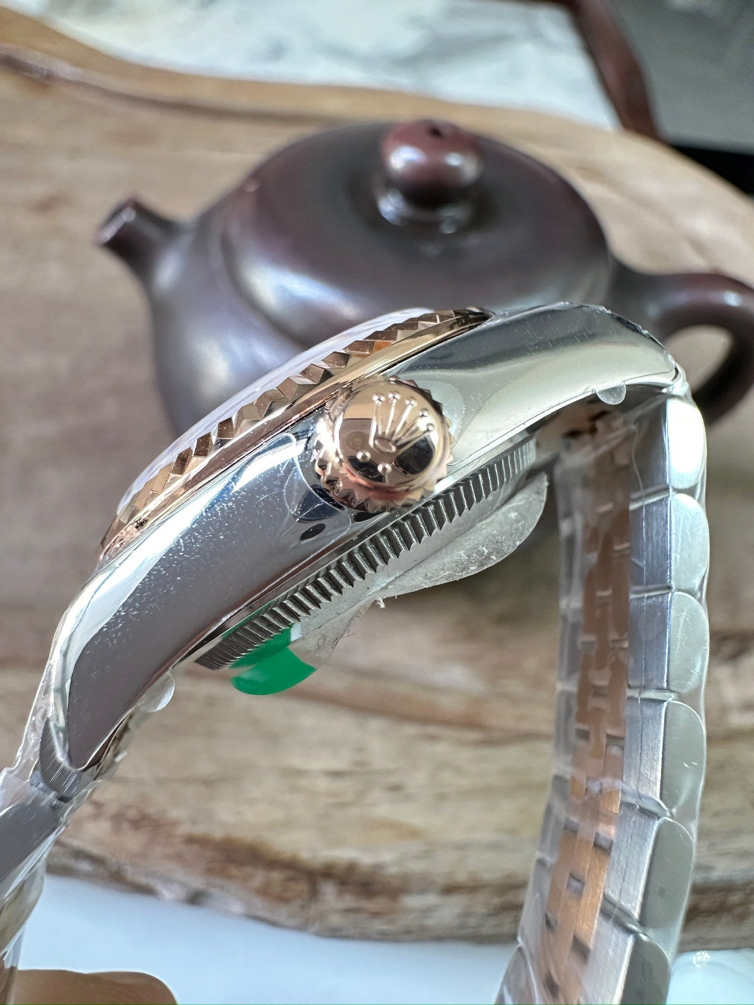 Rolex watch crown and case side, brushed metal with ridged bezel and green mark