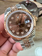 Rolex watch dial closeup, brown diamond markers, date window at 3 on bracelet