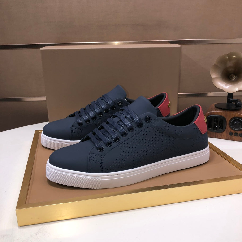 Burberry lace-up sneakers in dark navy, perforated uppers, red accents, white sole.
