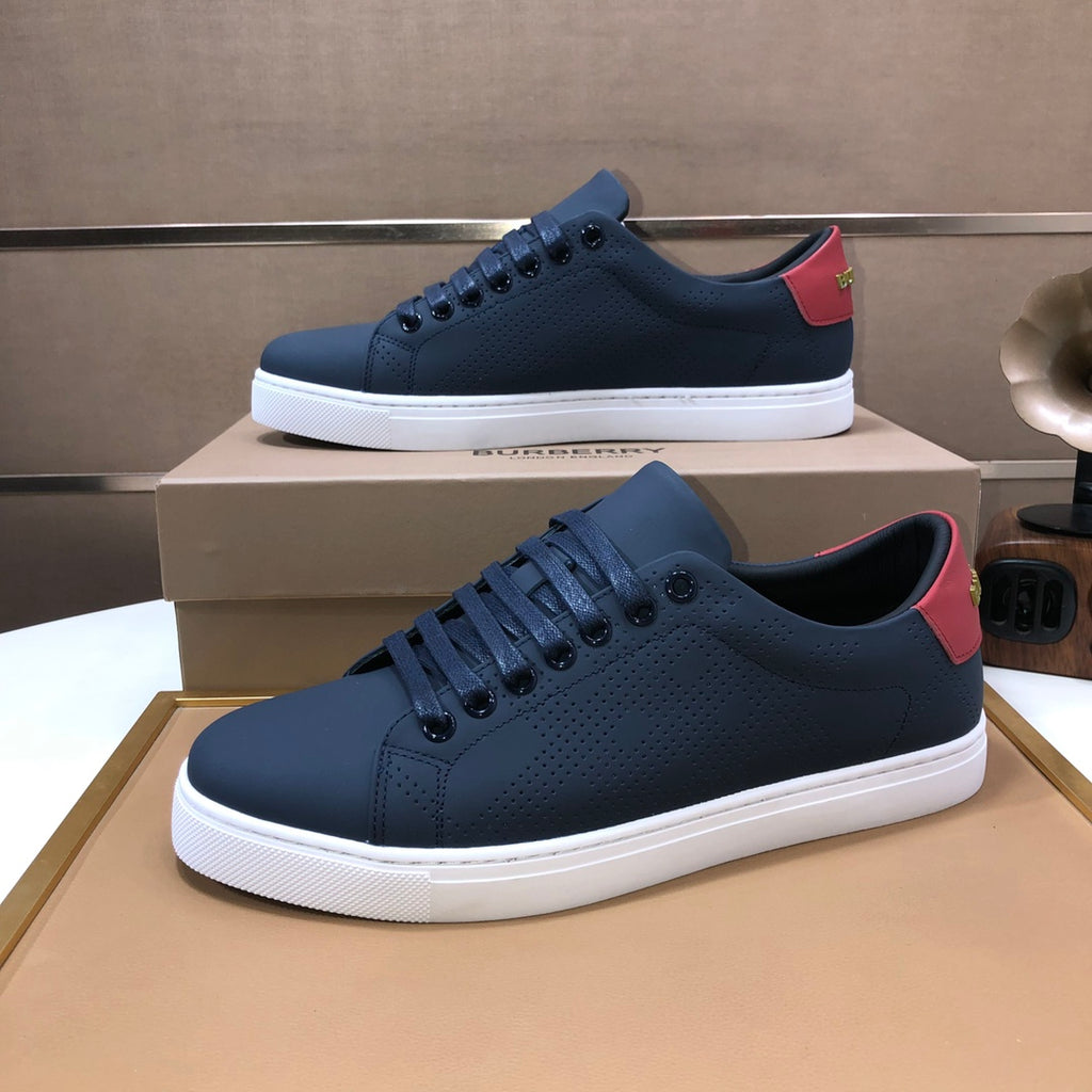 Burberry low-top sneakers in dark navy with red heel accents, leather, white sole.