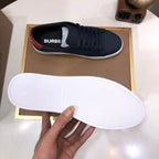 Burberry sneaker sole held up, white outsole with dark navy upper and red heel detail.