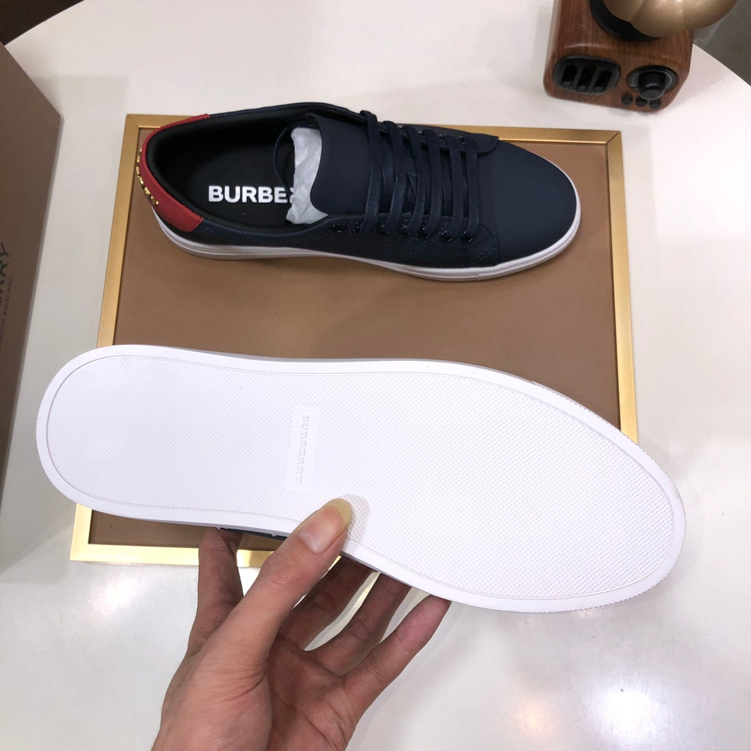 Burberry sneaker sole held up, white outsole with dark navy upper and red heel detail.