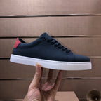 Burberry lace-up sneaker, dark navy upper with red heel tab and white sole.