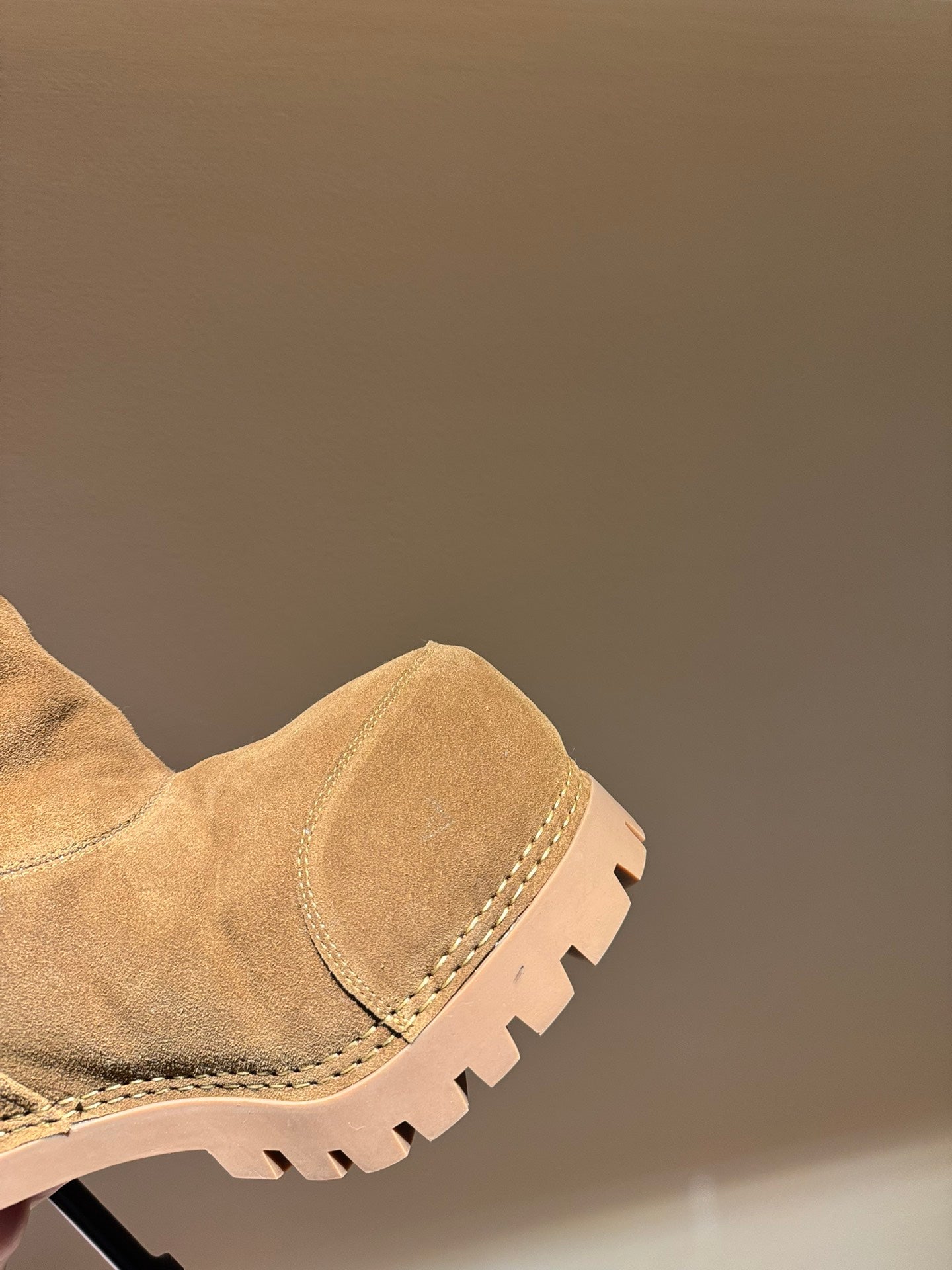 Tan suede knee-high boot with stitched cuff and chunky tread sole