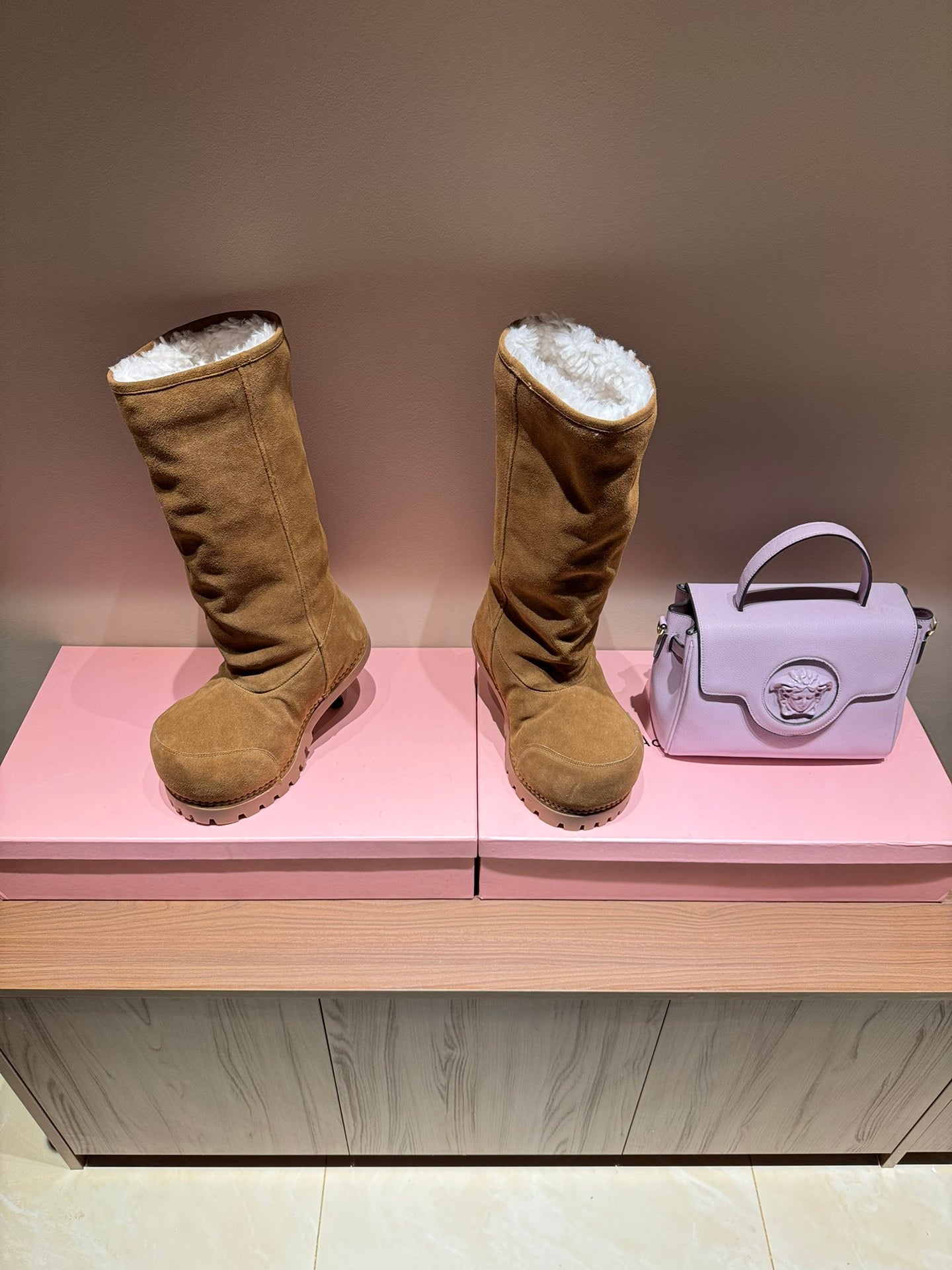 Tan suede knee-high boots with shearling cuffs and chunky tread sole