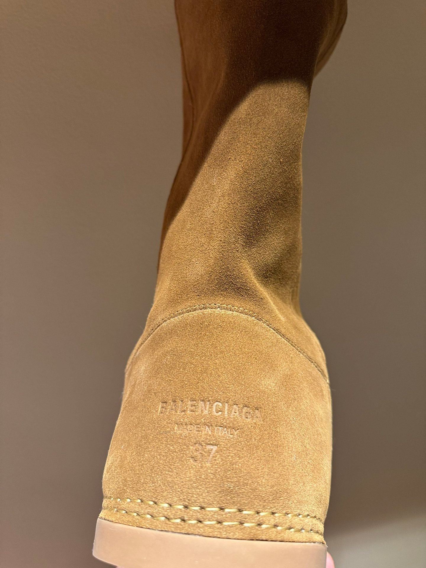 Tan suede knee-high boot with logo text on shaft and stitched outsole edge