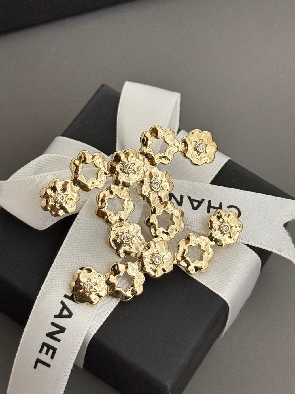 Chanel gold-tone statement brooch with floral charms on card, ribbon visible