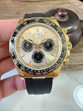 Rolex watch with gold case, black chronograph dial, gold bezel, black rubber strap.