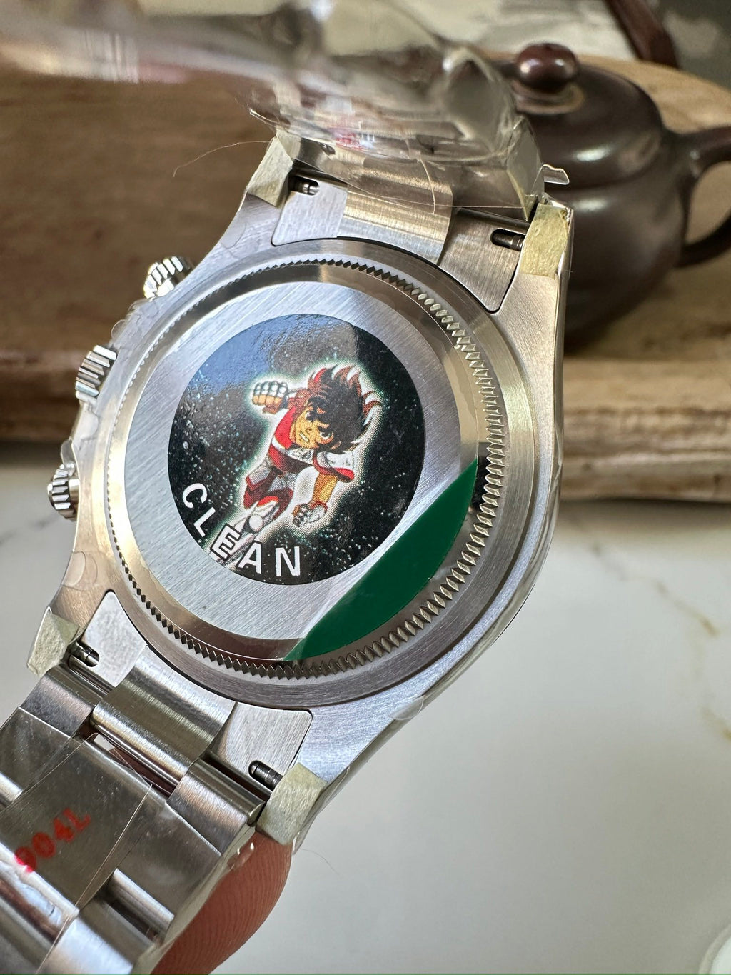 Stainless steel watch caseback with circular engraved design and green panel