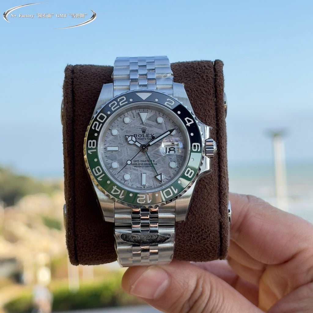 Rolex watch centered on brown cushion, grey dial, blue-green bezel, steel bracelet
