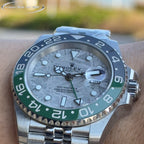 Rolex watch face close-up, grey dial, blue bezel with green ring, steel bracelet