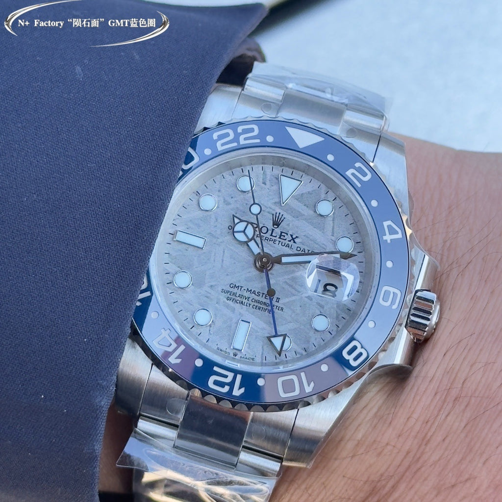 Rolex GMT-style watch with blue bezel and dial, steel bracelet, on dark cloth strap