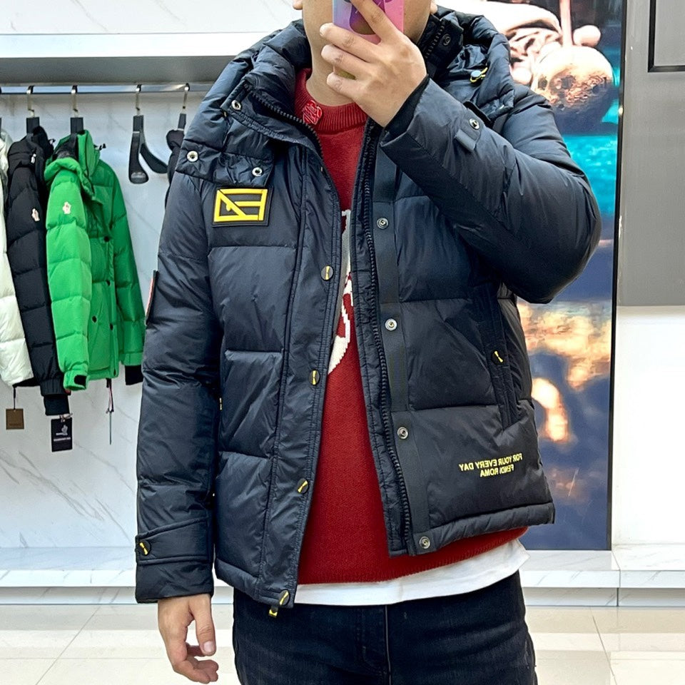 Dark hooded puffer jacket worn with front zipper and yellow logo patch