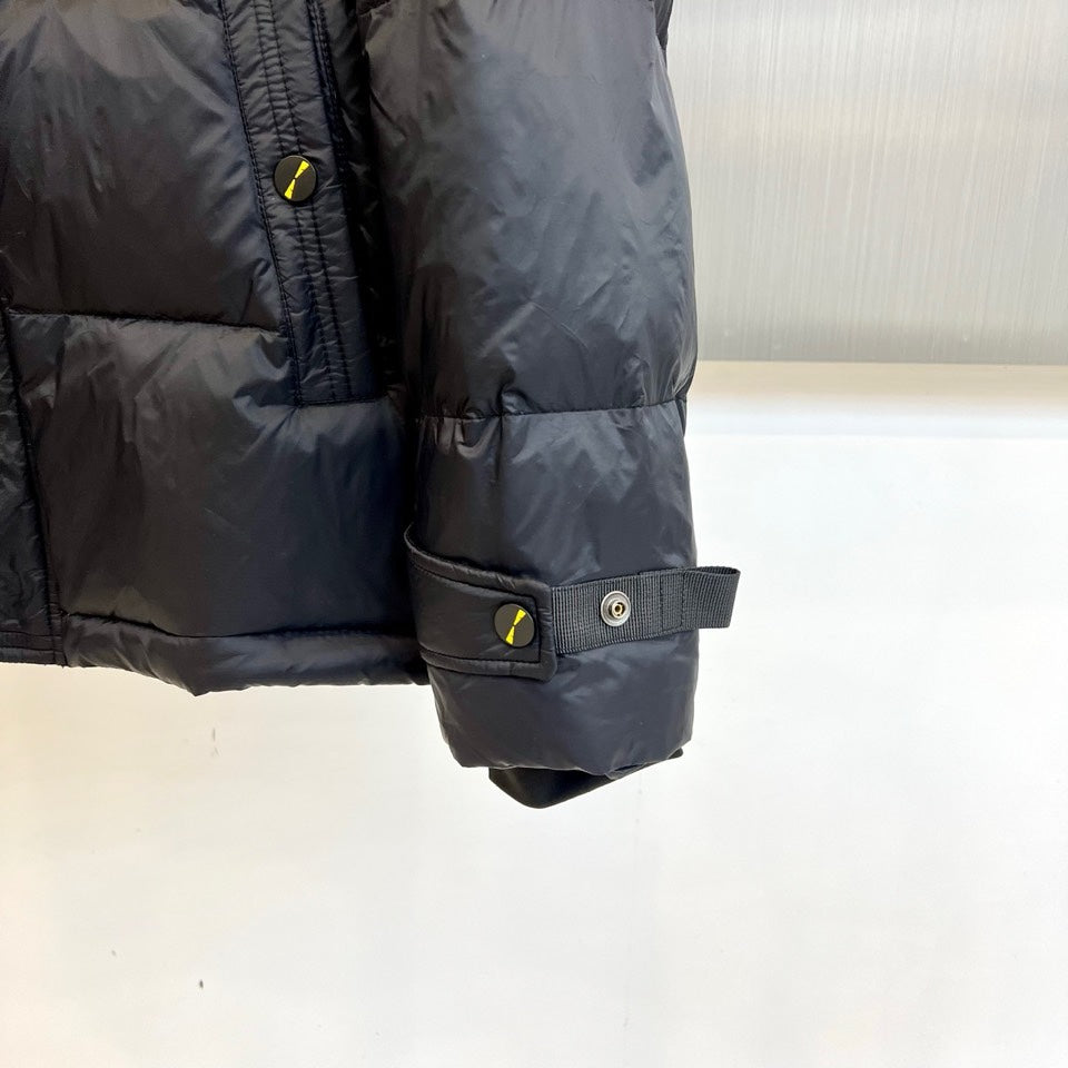 Dark puffer jacket sleeve with adjustable cuff strap and snap button