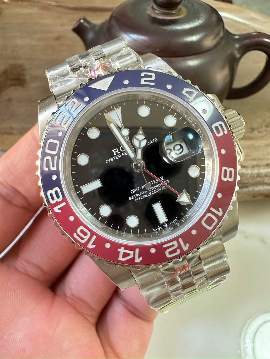 Rolex GMT watch front view with black dial, blue/red bezel, metal link bracelet