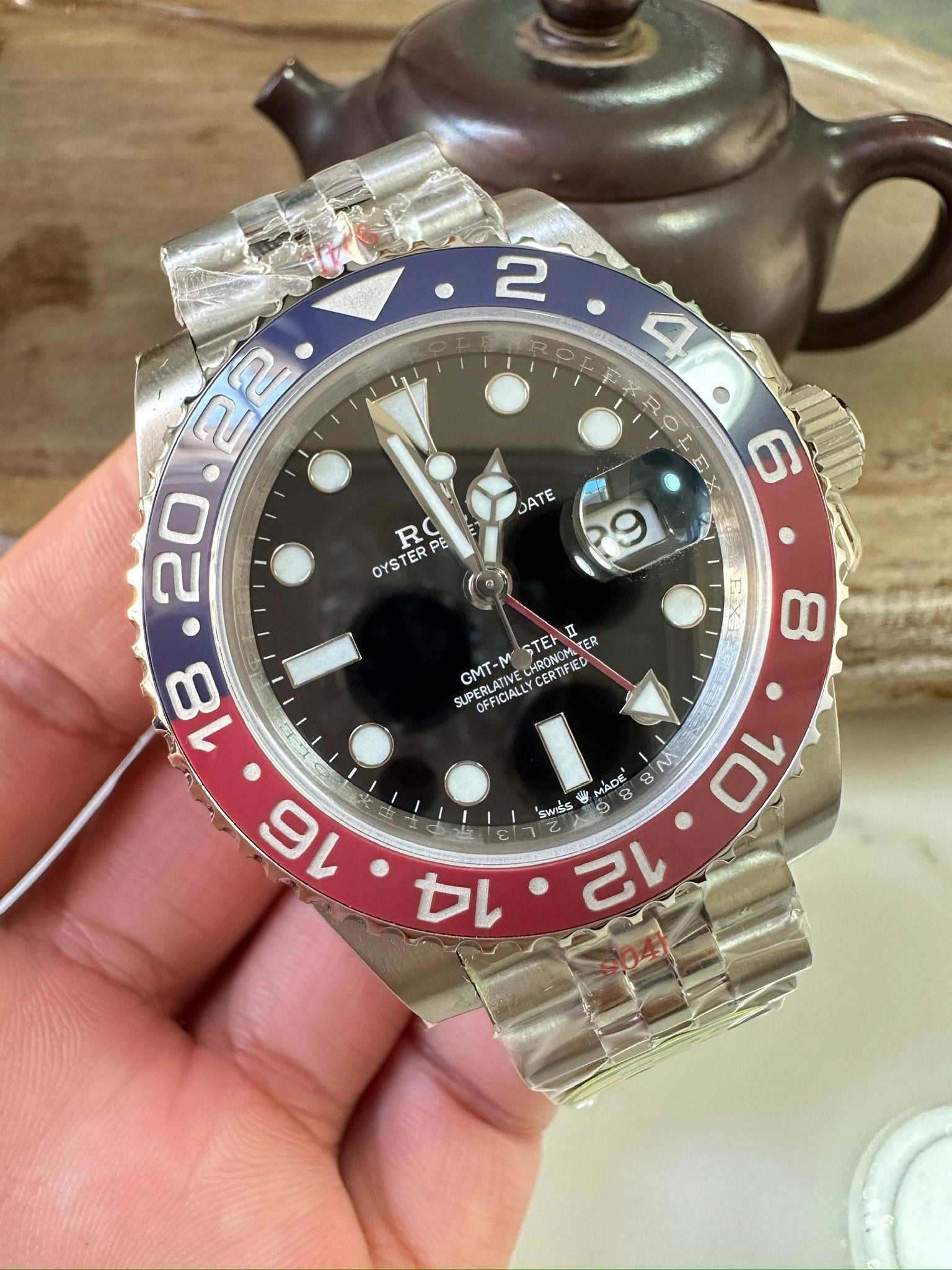 Rolex GMT watch front view with black dial, blue/red bezel, metal link bracelet