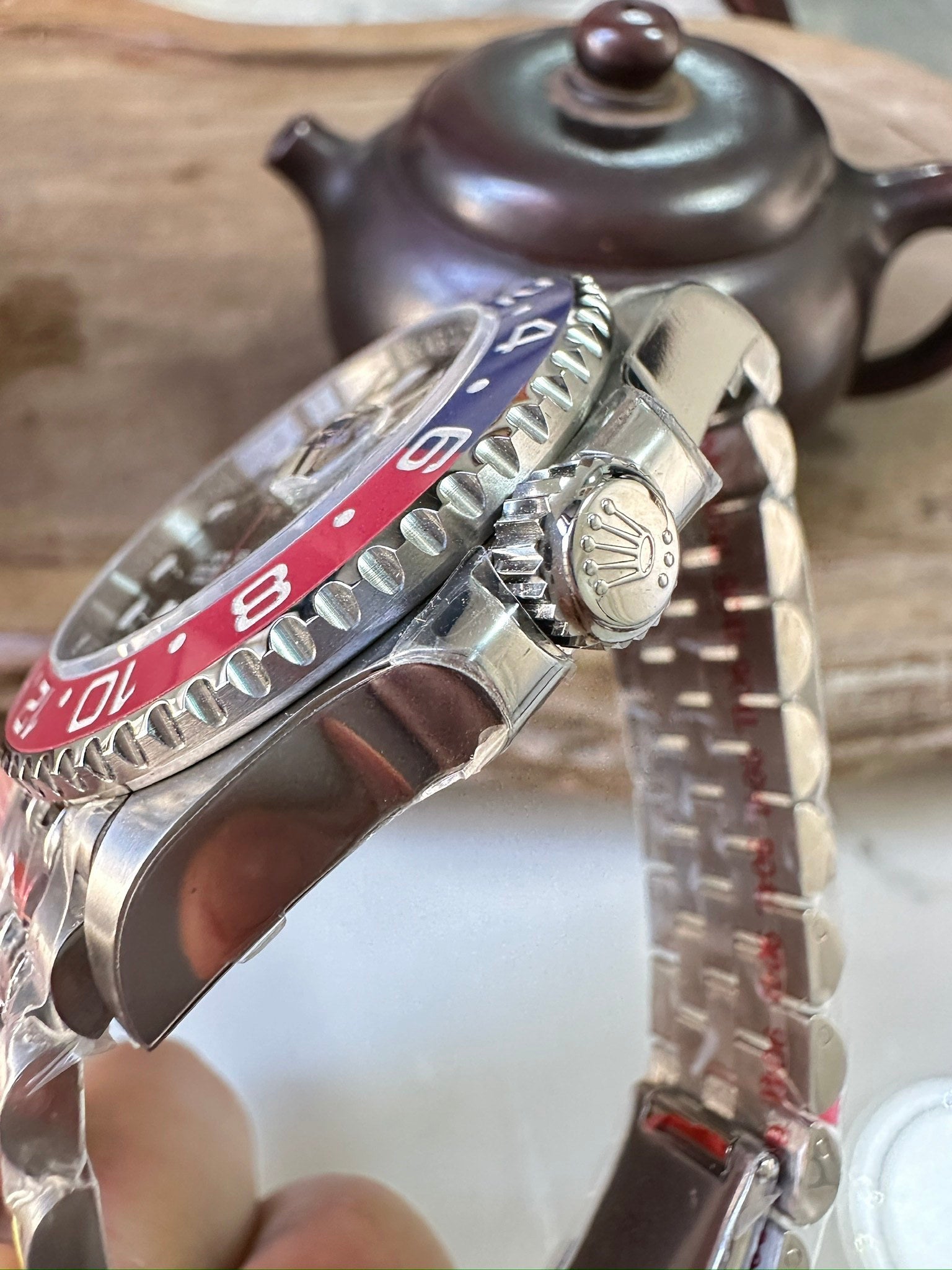 Rolex GMT watch side view with silver crown, blue/red bezel, metal bracelet